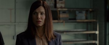 Movie still from “The Heat” (2013), directed by Paul Feig – A woman in a suit looking at the camera; Close Up shot, Over the shoulder angle