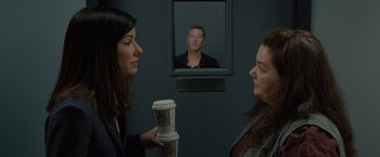 Movie still from “The Heat” (2013), directed by Paul Feig – Two women are holding coffee cups in front of a picture of a man; Medium shot, Over the shoulder angle