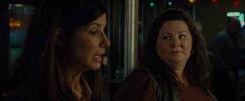 Movie still from “The Heat” (2013), directed by Paul Feig – Two women sitting next to each other in a dark room; Close Up shot, Over the shoulder angle
