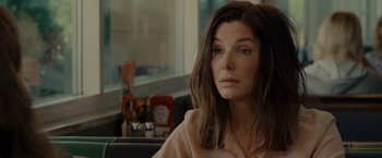 Movie still from “The Heat” (2013), directed by Paul Feig – A person sitting in front of a window; Close Up shot, Over the shoulder angle