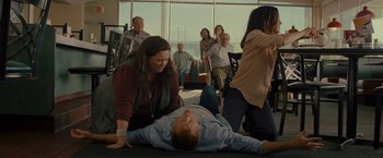 Movie still from “The Heat” (2013), directed by Paul Feig – A man laying on the ground in front of a group of people; Wide shot, High angle