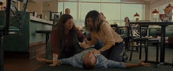 Movie still from “The Heat” (2013), directed by Paul Feig – A man lying on the ground while two other people look on; Medium shot, High angle