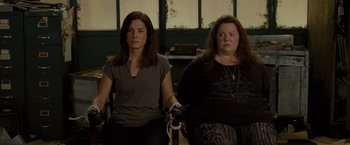 Movie still from “The Heat” (2013), directed by Paul Feig – Two women holding wii remotes while sitting in a room; Medium shot, High angle