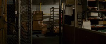 Movie still from “The Heat” (2013), directed by Paul Feig – Boxes are stacked on a cart in a warehouse; Wide shot, High angle
