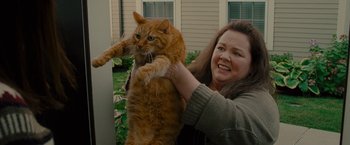 Movie still from “The Heat” (2013), directed by Paul Feig – A woman holding an orange cat on her arm; Medium shot, Low angle