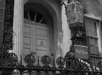 Movie still from “The Heiress” (1949), directed by William Wyler – A black - and - white photo of a building with a wrought - iron fence; Wide shot, Low angle