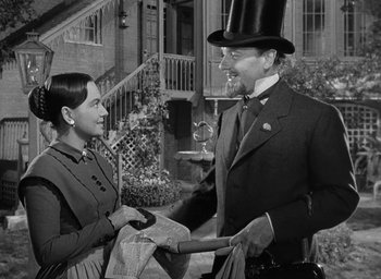 Movie still from “The Heiress” (1949), directed by William Wyler – A man and a woman wearing a top hat and holding newspapers; Medium shot, Over the shoulder angle