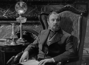 Movie still from “The Heiress” (1949), directed by William Wyler – A man sitting in a chair in front of a lamp; Medium shot, Low angle