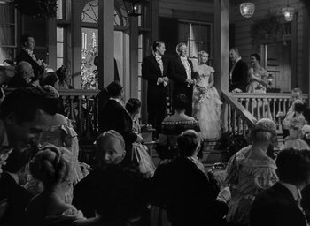 Movie still from “The Heiress” (1949), directed by William Wyler – A black and white photo of people standing on a porch; Wide shot, Low angle