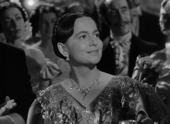 Movie still from “The Heiress” (1949), directed by William Wyler – A woman wearing a necklace and a dress in front of a crowd; Close Up shot, Over the shoulder angle