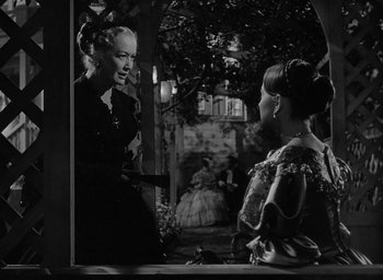 Movie still from “The Heiress” (1949), directed by William Wyler – Two women are talking to each other in a black and white photo; Medium shot, Over the shoulder angle