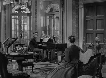 Movie still from “The Heiress” (1949), directed by William Wyler – A man and a woman are playing piano in a living room; Wide shot, High angle