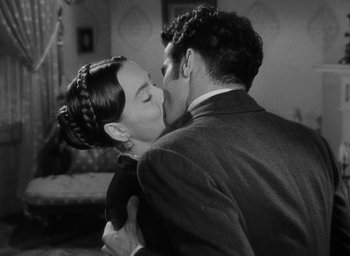 Movie still from “The Heiress” (1949), directed by William Wyler – A man and a woman kissing each other in front of a couch; Close Up shot, High angle