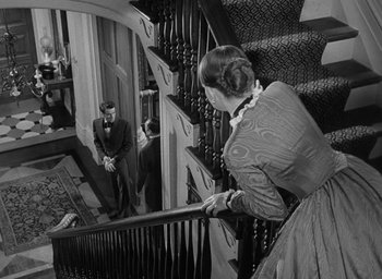 Movie still from “The Heiress” (1949), directed by William Wyler – An old photo of a man and a woman on the stairs; Wide shot, High angle