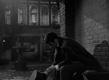 Movie still from “The Heiress” (1949), directed by William Wyler – A black and white photo of a man in a suit and hat; Wide shot, Low angle