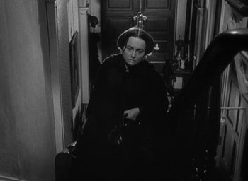Movie still from “The Heiress” (1949), directed by William Wyler – A man with a hat and a bag in a hallway; Medium shot, High angle