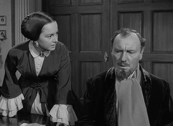 Movie still from “The Heiress” (1949), directed by William Wyler – An old photo of a man and a woman; Medium shot, Over the shoulder angle