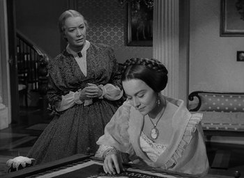Movie still from “The Heiress” (1949), directed by William Wyler – Two women in old - fashioned dresses are playing a board game together; Medium shot, High angle