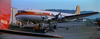 Movie still from “The High and the Mighty” (1954), directed by William A. Wellman – An airplane is being worked on at an airport; Wide shot, Low angle