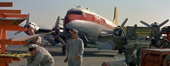 Movie still from “The High and the Mighty” (1954), directed by William A. Wellman – A man standing in front of an airplane on a runway; Wide shot, Low angle