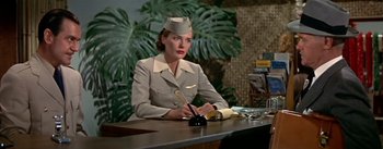 Movie still from “The High and the Mighty” (1954), directed by William A. Wellman – A woman sitting at a table writing on a paper; Medium shot, Low angle