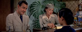 Movie still from “The High and the Mighty” (1954), directed by William A. Wellman – A woman is writing on a piece of paper while sitting at a table; Medium shot, Over the shoulder angle