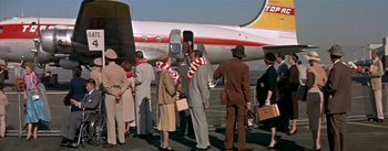 Movie still from “The High and the Mighty” (1954), directed by William A. Wellman – A group of people standing next to an airplane; Wide shot, High angle