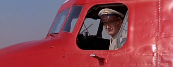 Movie still from “The High and the Mighty” (1954), directed by William A. Wellman – An older man in a pilot's hat sitting in a plane; Medium shot, Low angle
