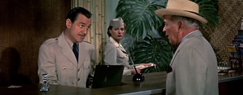 Movie still from “The High and the Mighty” (1954), directed by William A. Wellman – A man and a woman standing at a counter; Medium shot, Over the shoulder angle