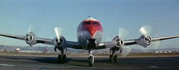 Movie still from “The High and the Mighty” (1954), directed by William A. Wellman – A red and white airplane on a runway; Extreme Wide shot, Low angle
