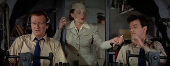 Movie still from “The High and the Mighty” (1954), directed by William A. Wellman – A woman in a military uniform standing next to a wall; Medium shot, Low angle