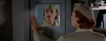 Movie still from “The High and the Mighty” (1954), directed by William A. Wellman – A woman in uniform looking in a mirror; Close Up shot, Over the shoulder angle