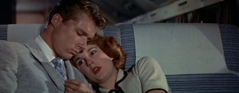 Movie still from “The High and the Mighty” (1954), directed by William A. Wellman – A man and a woman laying on a couch; Close Up shot, Overhead angle