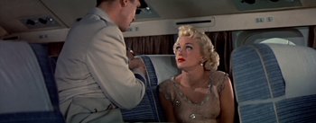 Movie still from “The High and the Mighty” (1954), directed by William A. Wellman – A man and a woman sitting in a car; Medium shot, High angle