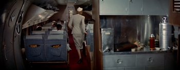 Movie still from “The High and the Mighty” (1954), directed by William A. Wellman – A stewardess is walking down the aisle of an airplane; Wide shot, High angle