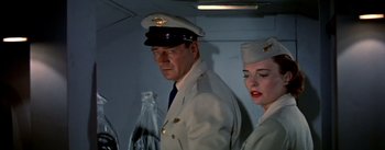 Movie still from “The High and the Mighty” (1954), directed by William A. Wellman – A man and a woman dressed in military uniforms; Medium shot, Low angle