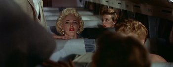 Movie still from “The High and the Mighty” (1954), directed by William A. Wellman – A woman with blonde hair sitting next to another woman on a plane; Medium shot, Low angle