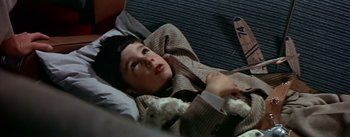 Movie still from “The High and the Mighty” (1954), directed by William A. Wellman – A woman laying on the ground in a room; Medium shot, Overhead angle
