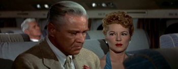 Movie still from “The High and the Mighty” (1954), directed by William A. Wellman – An older man and a younger woman are sitting on a plane; Close Up shot, Low angle