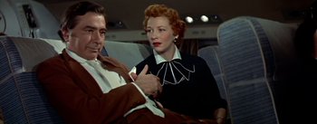 Movie still from “The High and the Mighty” (1954), directed by William A. Wellman – A man and a woman sitting next to each other on a train; Medium shot, Low angle