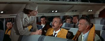 Movie still from “The High and the Mighty” (1954), directed by William A. Wellman – A man sitting on a seat on an airplane; Medium shot, Over the shoulder angle