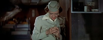 Movie still from “The High and the Mighty” (1954), directed by William A. Wellman – A woman in a uniform looking at her cell phone; Medium shot, Low angle