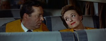 Movie still from “The High and the Mighty” (1954), directed by William A. Wellman – A man and a woman sitting next to each other on a bus; Close Up shot, High angle
