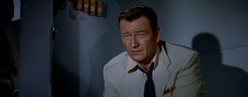 Movie still from “The High and the Mighty” (1954), directed by William A. Wellman – A person wearing a suit and tie; Close Up shot, Over the shoulder angle