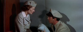 Movie still from “The High and the Mighty” (1954), directed by William A. Wellman – A man and a woman in military uniforms talking to each other; Medium shot, Low angle