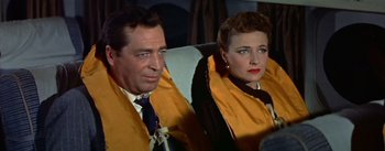 Movie still from “The High and the Mighty” (1954), directed by William A. Wellman – A man and a woman sitting next to each other on a couch; Medium shot, High angle