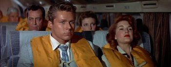 Movie still from “The High and the Mighty” (1954), directed by William A. Wellman – A man and two women are sitting on a plane; Medium shot, Low angle