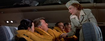 Movie still from “The High and the Mighty” (1954), directed by William A. Wellman – A man and woman in uniform talking to each other in an airplane; Medium shot, Low angle