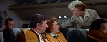 Movie still from “The High and the Mighty” (1954), directed by William A. Wellman – A man in a uniform is pointing at two women in yellow jackets; Medium shot, High angle