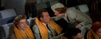 Movie still from “The High and the Mighty” (1954), directed by William A. Wellman – An airline stewardess giving a man a blanket; Medium shot, Over the shoulder angle